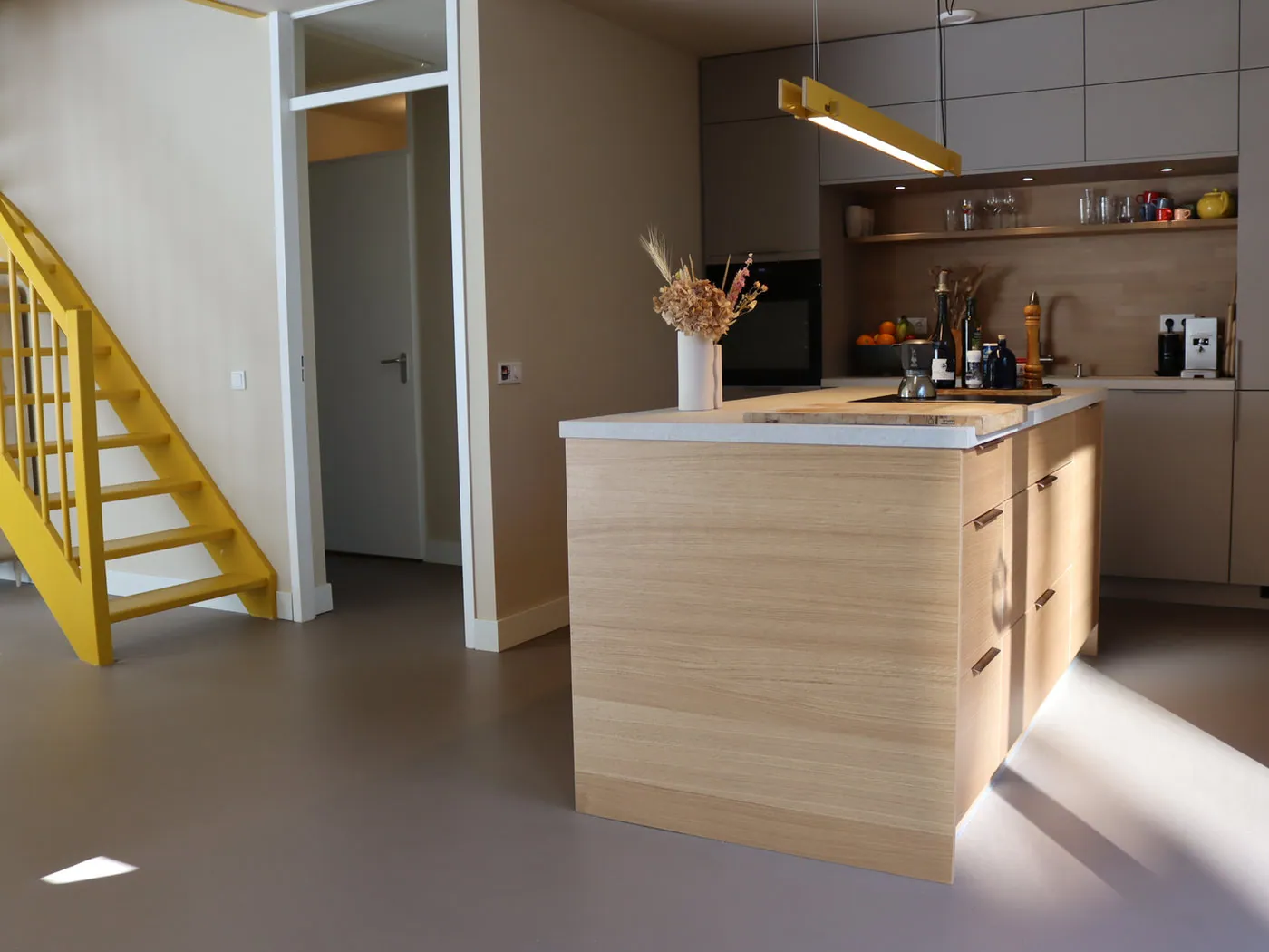 Keuken met houten eiland, daglicht en gele trap
